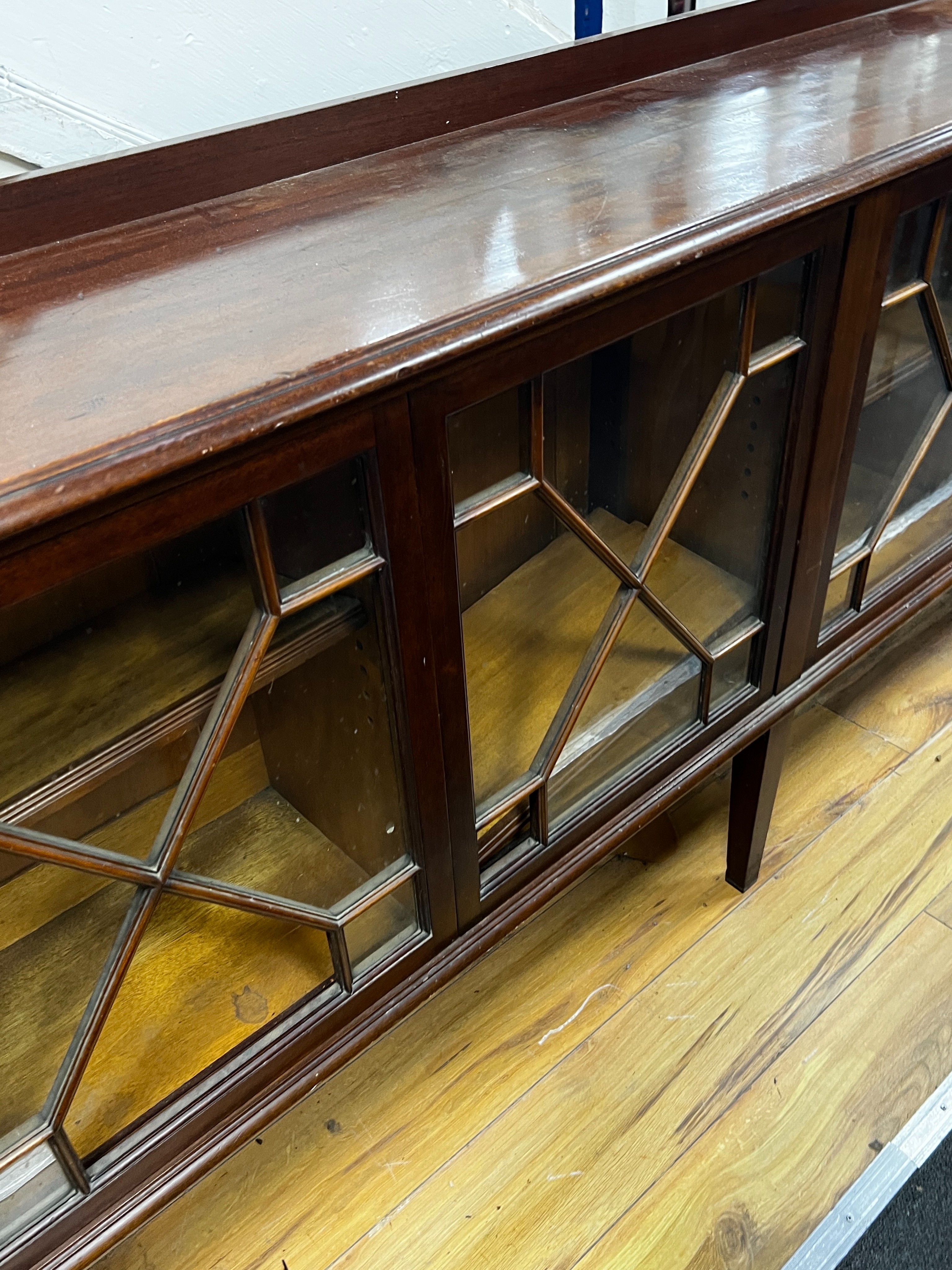 An Edwardian glazed mahogany dwarf bookcase, enclosed by six astragal glazed sliding doors, width 290cm, depth 34cm, height 94cm